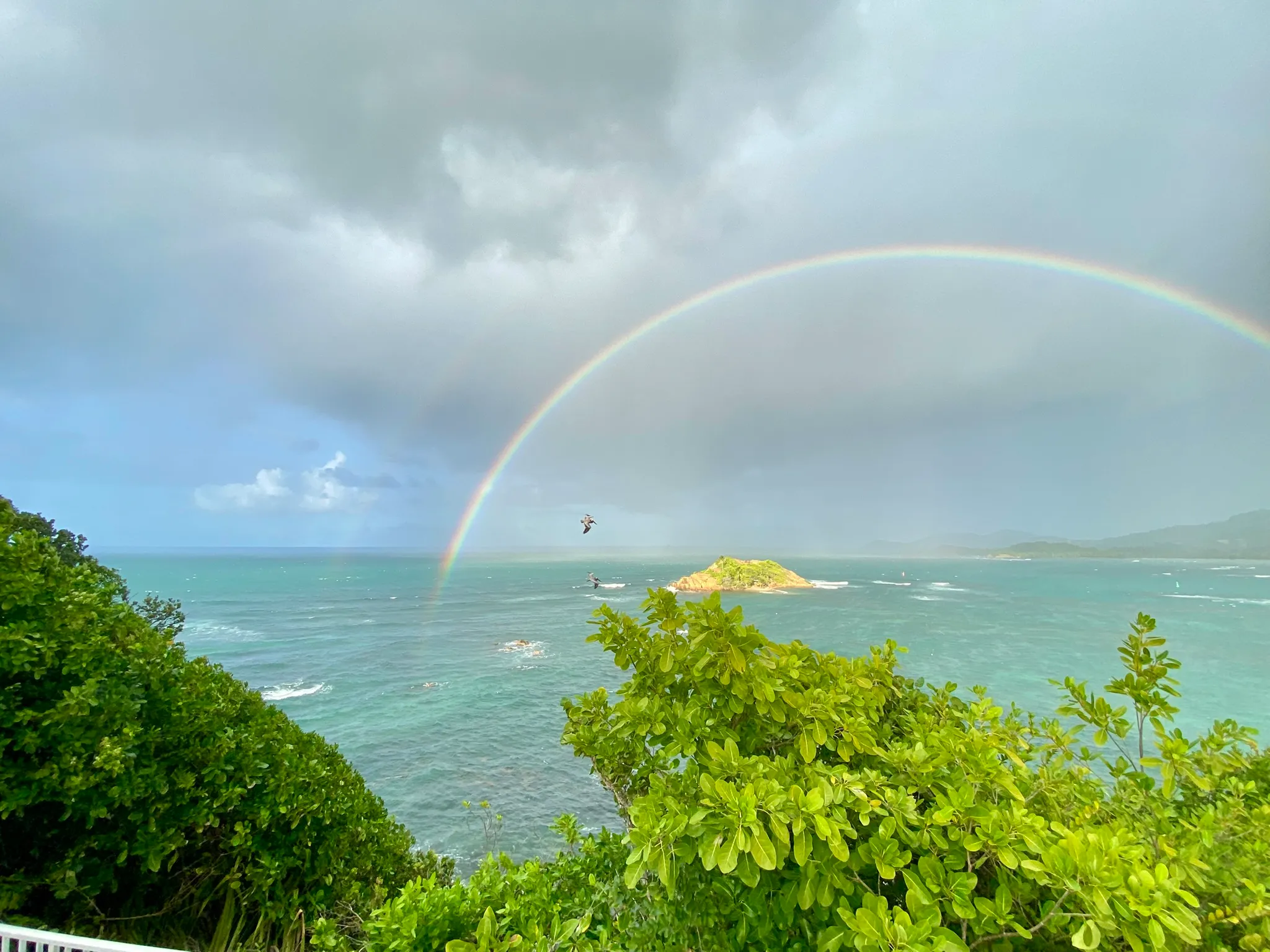 Arc-en-ciel au-dessus de la mer turquoise et d'un îlet, vue depuis la villa.