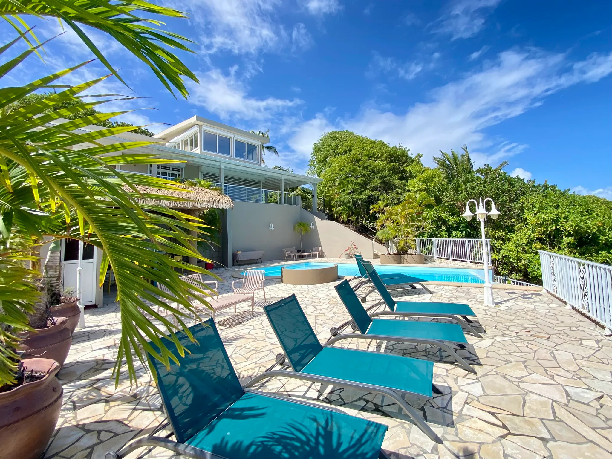 La Villa Kaïbana vue depuis la terrasse de la piscine, transats face à la baie.