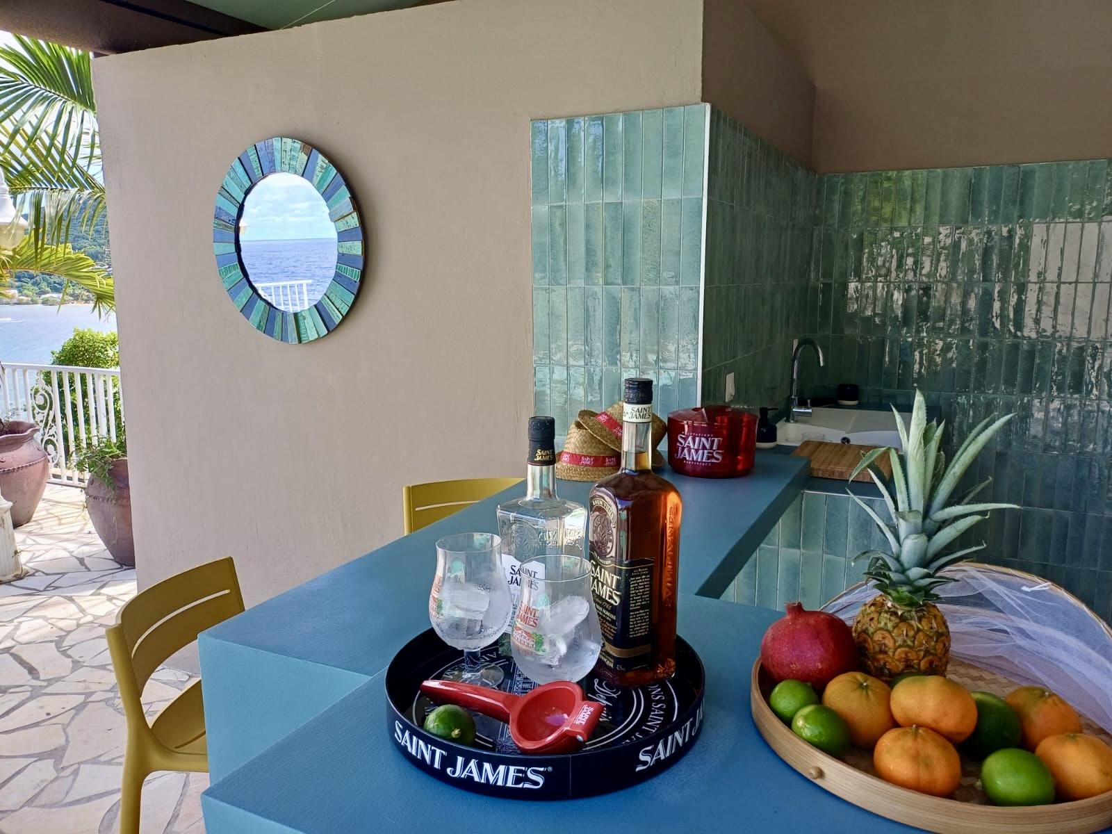 Bouteilles de rhum agricole Saint-James et fruits pays sur le bar de la villa, vue mer